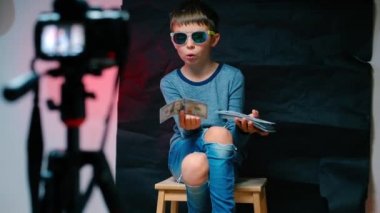 Çocuk video blogcusu kameraya parayı gösteriyor.