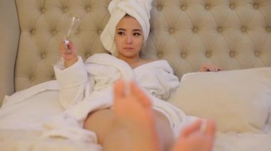 Kız lüks bir otelin yatağında kafasında havluyla yatıyor..