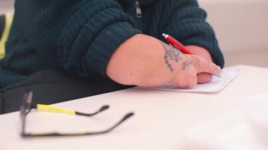 Masada kalemle oturan engelli kişinin eli kapanıyor..