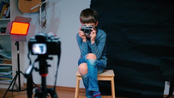 男の子は手にカメラを持ち、顔にカメラを置き、視力を始めます。. — ストック動画