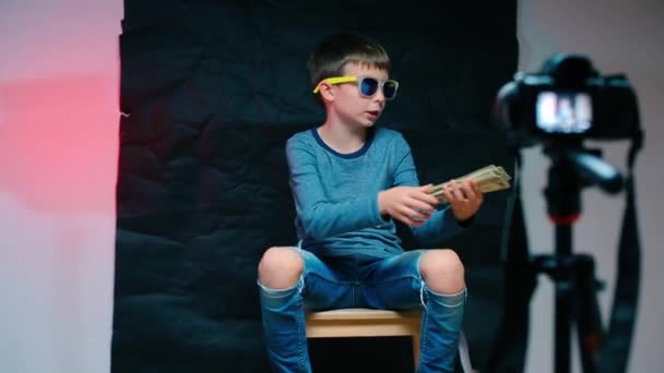 Dětský video blogger v brýlích drží peníze v rukou — Stock video