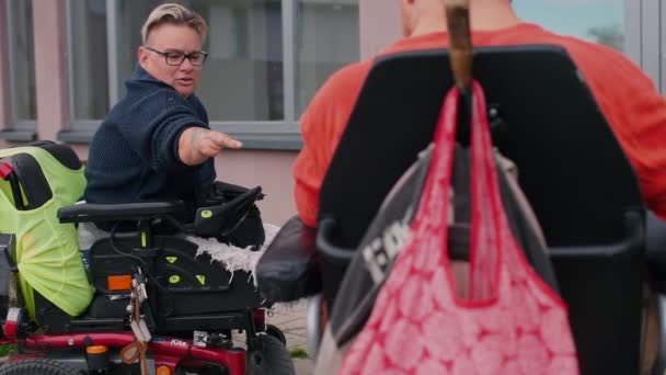 Dos personas con discapacidad sentadas en sillas de ruedas hablando en el patio de la casa — Vídeo de stock