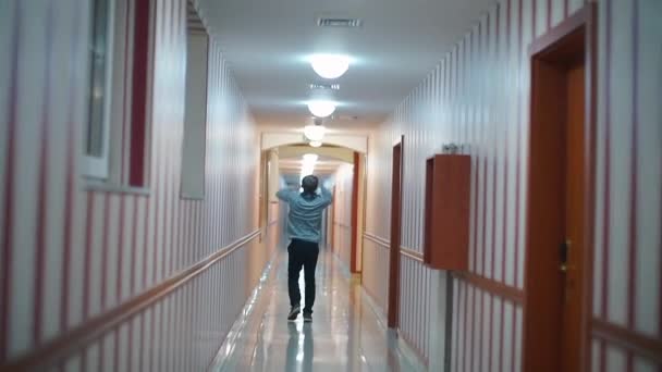 Um homem alegre corre ao longo do corredor do hotel . — Vídeo de Stock