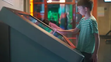 Çocuklar çocuk merkezinden geniş bir dokunmatik ekranla alışveriş yapıyorlar..