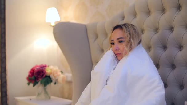 A zaklatott lányt fehér takaró borítja az ágyban. A lány PMS-ben lakik.. — Stock videók