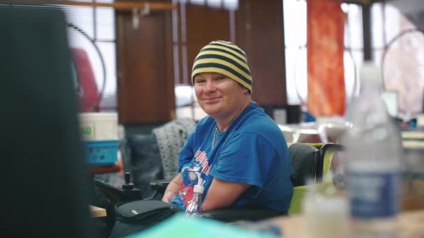 Un homme handicapé agite la main à la caméra 