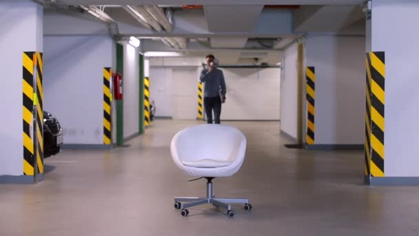 Un employé de bureau vient s'asseoir sur une chaise dans un garage souterrain . — Video