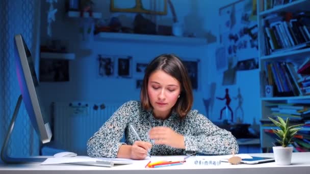 Una chica se sienta en una mesa y habla, se toca el pelo . — Vídeos de Stock