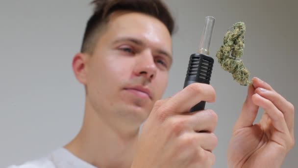 Portré egy fickóról, aki marihuánát tart és egy párologtatót, hasissal a kezében. — Stock videók