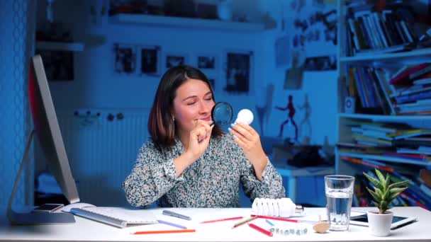 Estudiante estudia energía, examina una bombilla — Vídeos de Stock