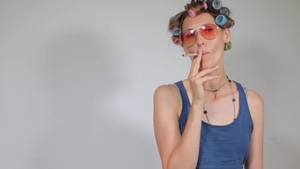 Mooie vrouw in krulspelden rookt marihuana — Stockvideo