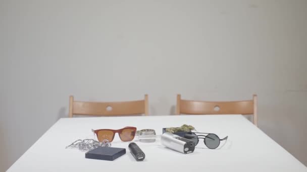 На столе находятся предметы современного курильщика марихуаны — стоковое видео