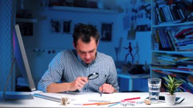 Masadaki adam büyüteçle okuyor..