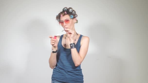 Cheerful, beautiful housewife in curlers sets fire to a joint with marijuana — Stock Video