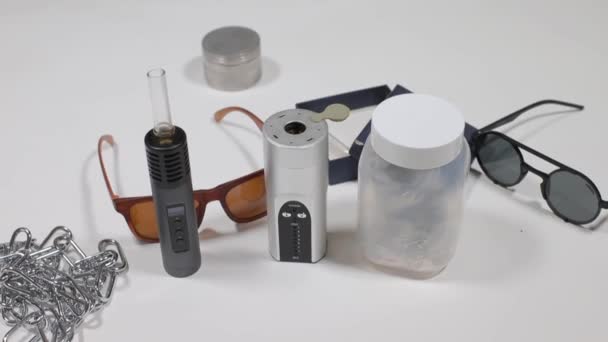 Two vaporizers stand on a table near a can of cannabis, using marijuana — Stock Video