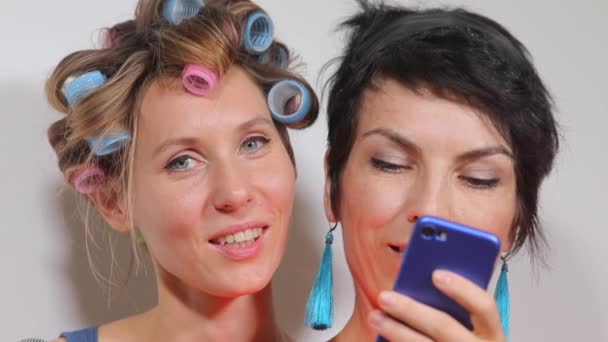 Две девушки смотрят на экран смартфона — стоковое видео