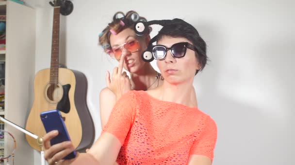 Meisje peuteren in haar neus, vriendin het nemen van selfie foto 's op de telefoon — Stockvideo