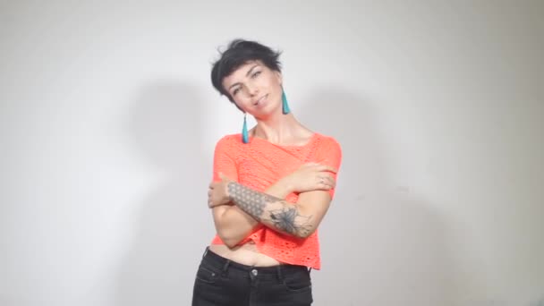 Дівчина в помаранчевій футболці з татуюванням на руці, танцює на вечірці — стокове відео