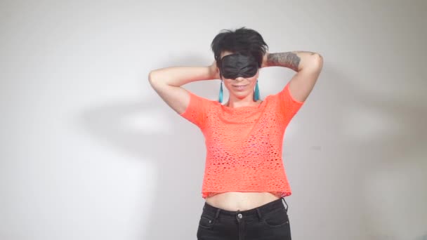 Девушка перед маской для сна, в оранжевой футболке с татуировкой на руке — стоковое видео