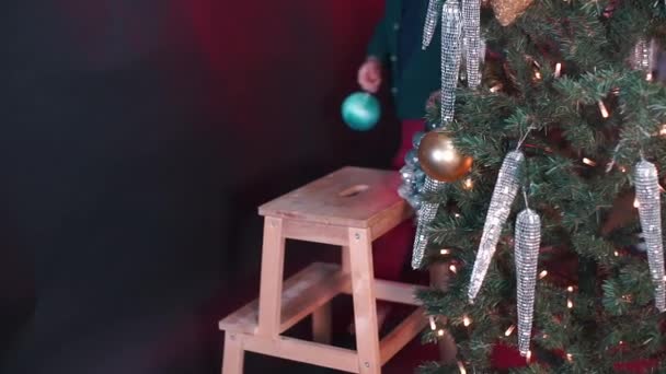 Ένα αγόρι στολίζει ένα χριστουγεννιάτικο δέντρο. — Αρχείο Βίντεο