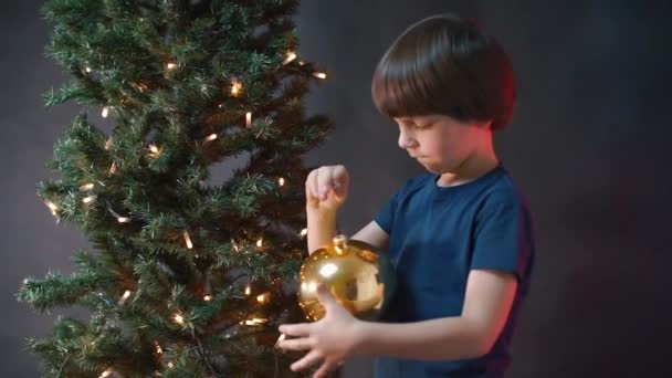 Il bambino tiene in mano un giocattolo natalizio. La esamina. — Video Stock