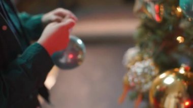 Çocuk Noel ağacına Noel topları asıyor..