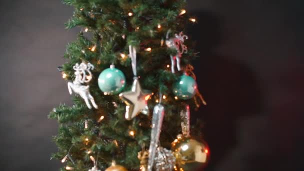 Das Kind hängt ein Weihnachtsspielzeug an den Weihnachtsbaum. — Stockvideo