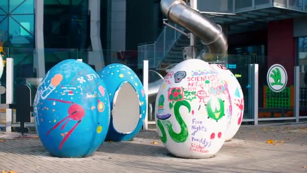 Grandes huevos de Pascua pintados están en la calle. El siguiente vidrio es el logotipo de Skoda . — Vídeos de Stock