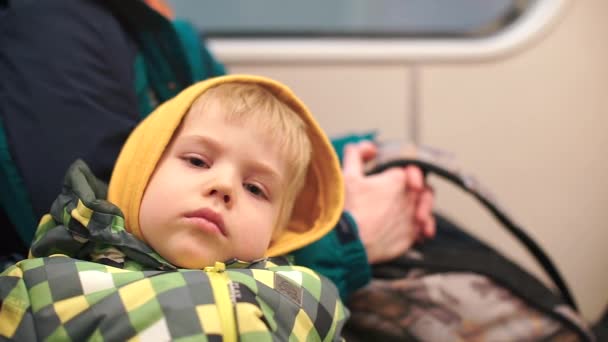 Un bel enfant en vêtements jaunes assis dans un train s'endort . — Video
