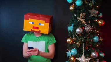 Kafasında kare maskeli bir adam akıllı telefon kullanıyor..