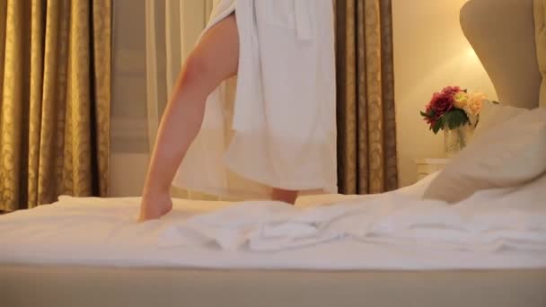 Asian girl stands on a bed in a hotel at a bachelorette party. — Stockvideo