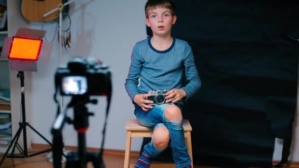 A child sits on a chair in front of a video camera. — Stockvideo