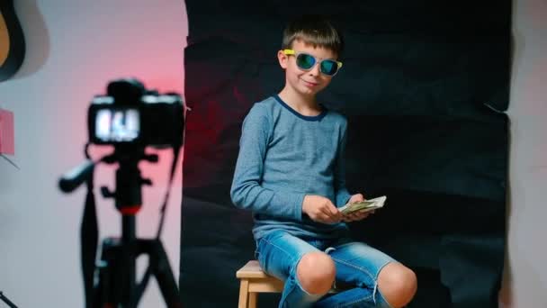 Un giovane video blogger ci getta dollari in una videocamera . — Video Stock