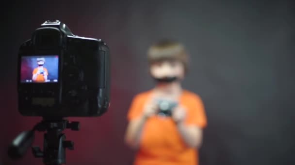 Een video blogger met masking tape op zijn gezicht neemt een video op over de camera. — Stockvideo