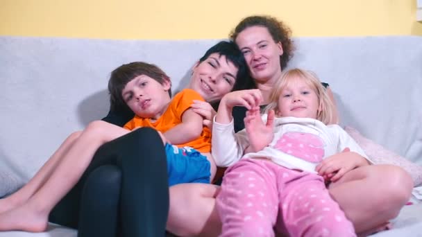 Due bambini e due donne si abbracciano sul divano . — Video Stock