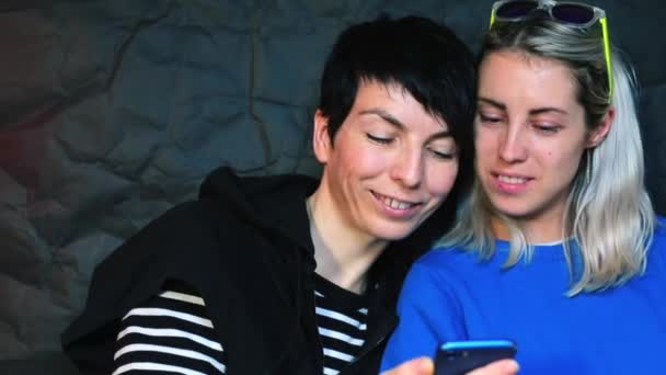 Dos lesbianas están mirando la pantalla de un smartphone . — Vídeos de Stock