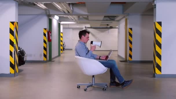 Un homme est assis sur une chaise pivotante dans le parking d'un garage souterrain . — Video