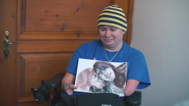En handikappet person holder et bilde tegnet av ham i hendene. . – stockvideo