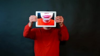 Adam elinde bir tablet tutuyor ve bir adamın dudaklarını kapatıyordu.