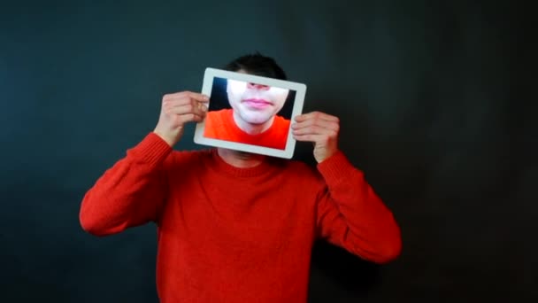 Ein Mann hält eine Tablette auf dem Bildschirm, von der ein Mann Kaugummi kaut. — Stockvideo