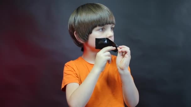 Imitatie van kindermisbruik, een kind met een zwart lint op zijn lippen. — Stockvideo