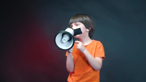 A boy with a sealed mouth shouts into a megaphone. — Stock Video