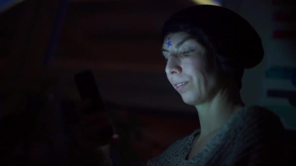 Дівчина з зіркою на лобі використовує смартфон вночі . — стокове відео