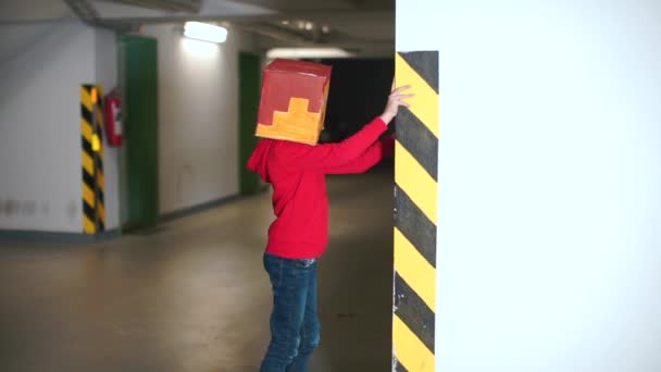 Мальчик в маске стоит рядом со стеной в подземном гараже . — стоковое видео