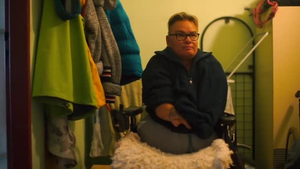Uma pessoa com deficiência tira a camisola no corredor do apartamento . — Vídeo de Stock