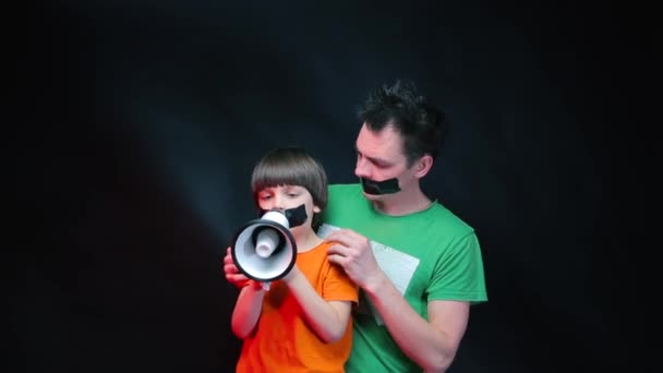 Un homme et un enfant avec la bouche collée protestation, criant dans un mégaphone . — Video