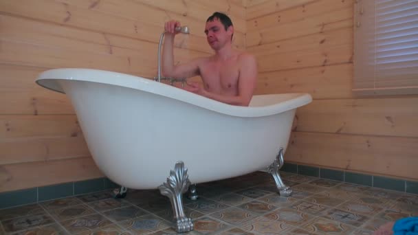 Un hombre toma una ducha mientras está sentado en el baño . — Vídeo de stock