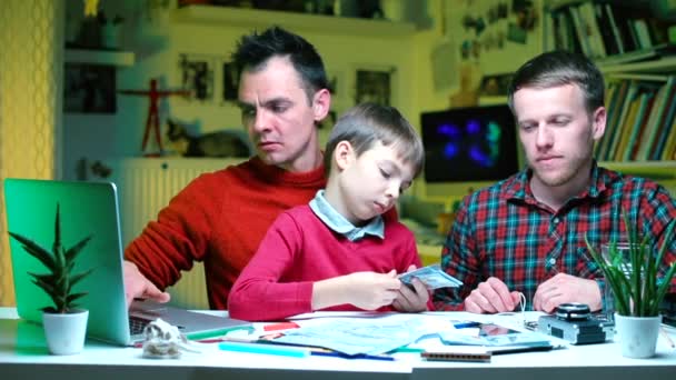 Dos profesores enseñan al niño ciencias financieras en la escuela . — Vídeos de Stock