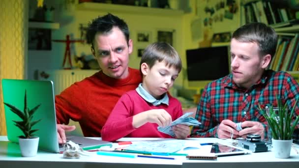 Dos hombres de negocios y un niño están sentados a la mesa . — Vídeo de stock