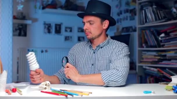 The guy examines the light bulb, wearing a hat on his head — Stock Video